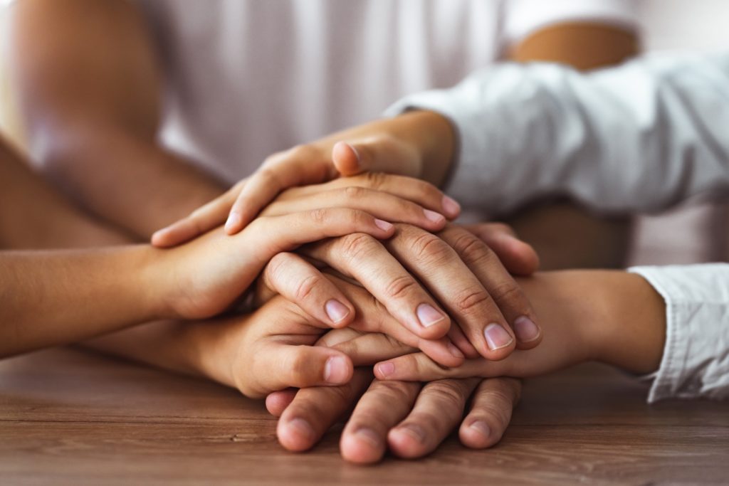 caring family hold hands together at table